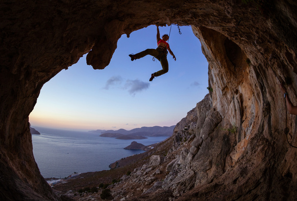 Young woman climbing in cave at sunset - Photo, Image
