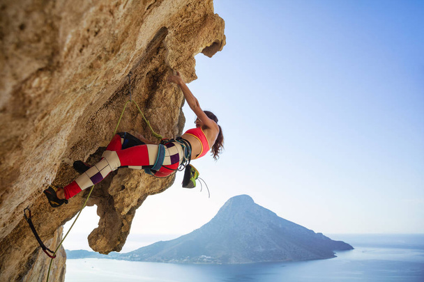 Genç kadın taşkın cliff tırmanmak için mücadele - Fotoğraf, Görsel