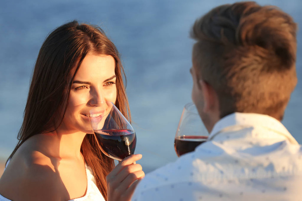 Young couple with wine having romantic date on sunset beach - Zdjęcie, obraz