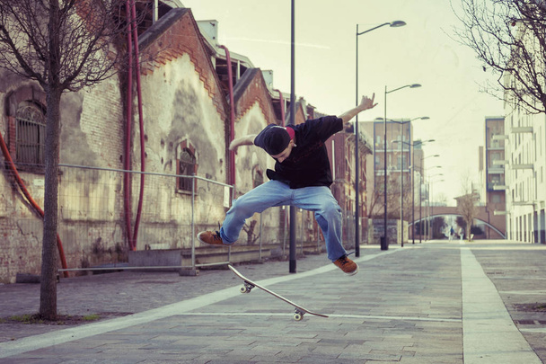 young boy jumping with skateboard in outskirt street - Фото, изображение