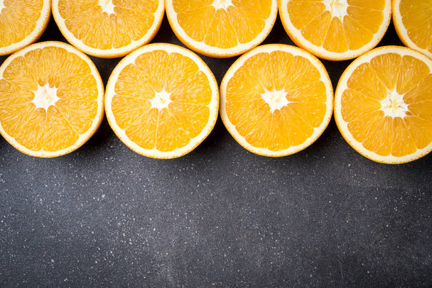 Fresh and juicy half cut oranges on dark stone table - Foto, Imagem