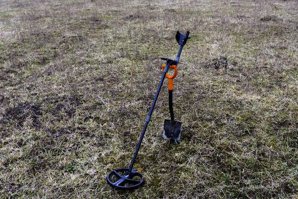 Een apparaat voor het vinden van schatten met een schop op het gras - Foto, afbeelding