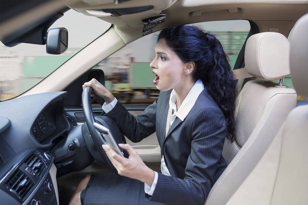 Bizneswoman z cellphone jazdy samochodem - Zdjęcie, obraz