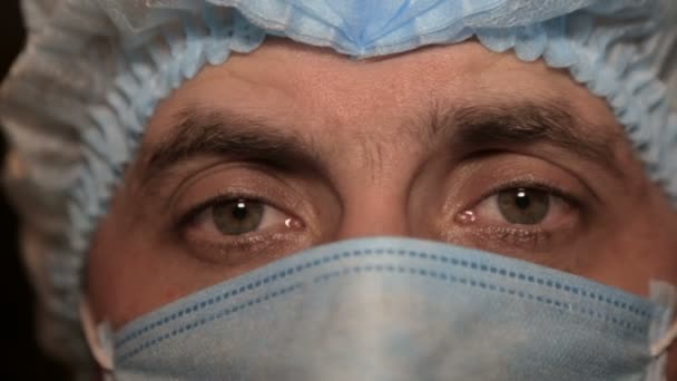 Close-up of a doctors face in a medical mask, after surgery - Πλάνα, βίντεο