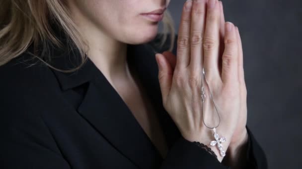 young woman is praying. close-up female hands holding chain with a cross - Felvétel, videó
