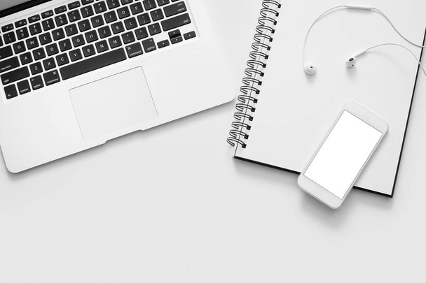 Laptop, phone, notebook and earphones on white background - Photo, Image