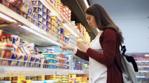 Fiatal nő vásárol a szupermarketben a sajt. - Felvétel, videó