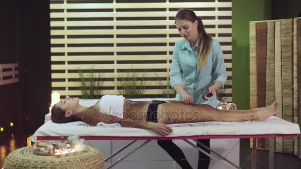 Spa-behandeling in de schoonheidssalon, maakt de masseur een scrub voor het meisje - Video
