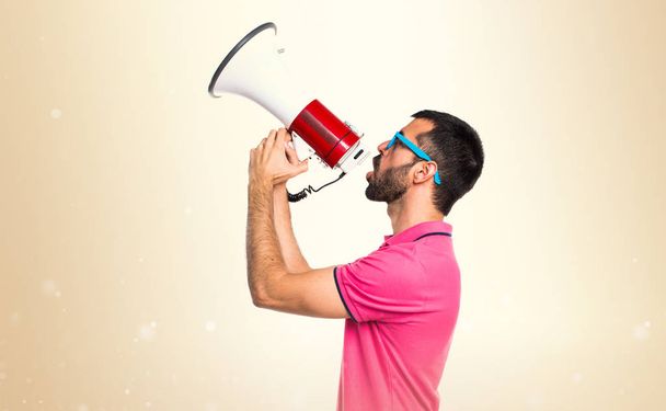 Άνθρωπος με πολύχρωμα ρούχα φωνάζοντας από το megaphone σε ώχρα backgro - Φωτογραφία, εικόνα