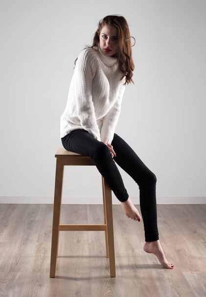 Красива модель жінка сидить на дерев'яному стільці
 - Фото, зображення