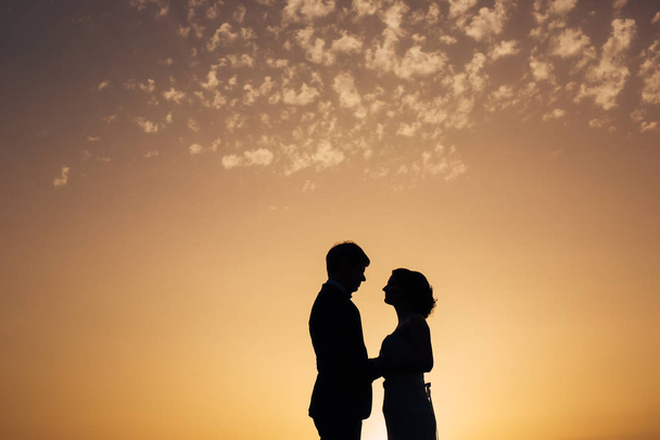 Silhouette des jeunes mariés contre le ciel au coucher du soleil. Mariage i
 - Photo, image