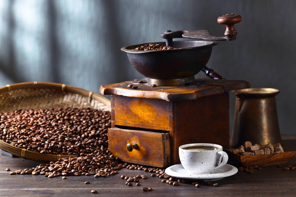 Kuppi mustaa kahvia, kahvimylly ja paahdettuja papuja
 - Valokuva, kuva