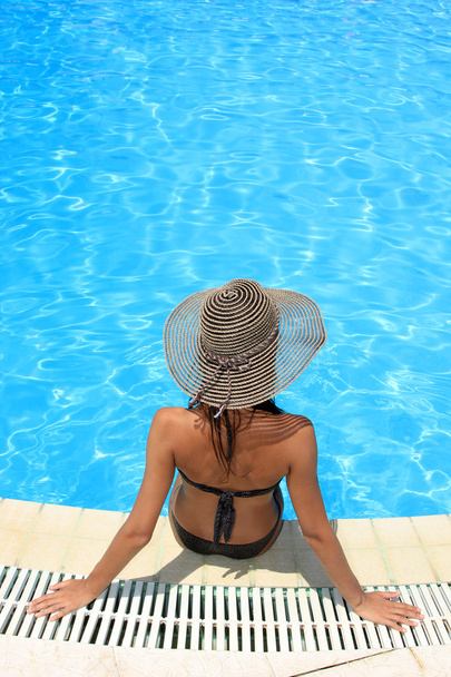 woman sitting on the ledge of the pool. - Фото, изображение