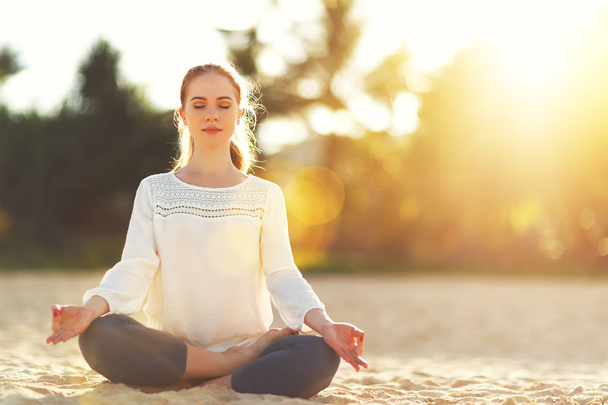 Kobieta uprawia jogę i medytuje w pozycji lotosu na plaży - Zdjęcie, obraz