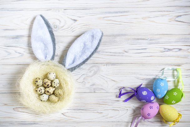 Een nest met gekleurde paaseieren en bunny oren thuis op Paasdag. Vieren Pasen in het voorjaar. Eieren schilderen. - Foto, afbeelding