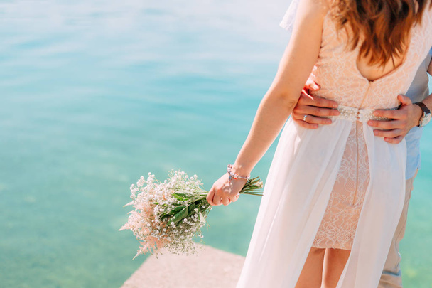 O noivo abraça a noiva na praia. Casamento em Montenegro
 - Foto, Imagem