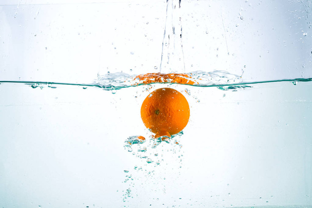 Orange in streams of water on a white background - Fotoğraf, Görsel
