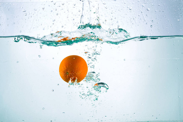 Orange in streams of water on a white background - Zdjęcie, obraz