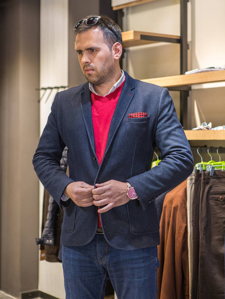 Happy young man choosing jacket in mall or clothing store. sale, - Foto, Imagem