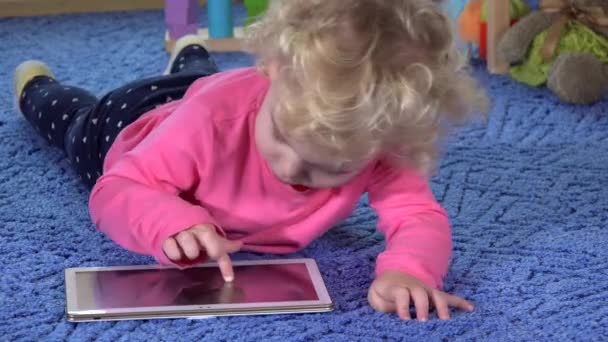 Schattig klein meisje op de maag liggen en gebruik van tablet pc - Video