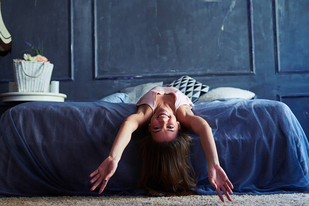 Смішна молода жінка з застібнутими руками лежить на ліжку
 - Фото, зображення