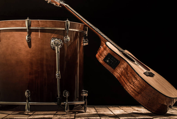 μουσικά όργανα, μπάσο τύμπανο και ακουστική κιθάρα πάνω σε μαύρο φόντο - Φωτογραφία, εικόνα