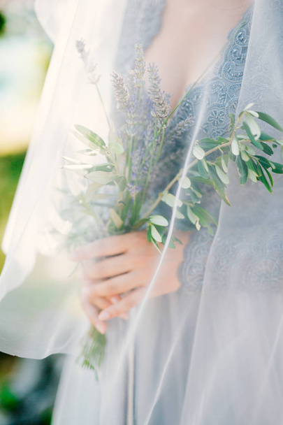 Lavender Wedding bouquet in hands of the bride under veil in pal - Foto, imagen