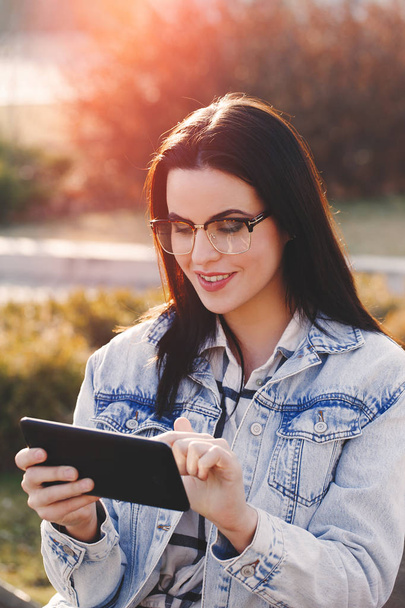 Inteligente jovem na moda mulher se comunicando por tablet ao ar livre
 - Foto, Imagem