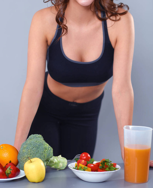 Young and beautiful  woman standing near desk with vegetables - Φωτογραφία, εικόνα