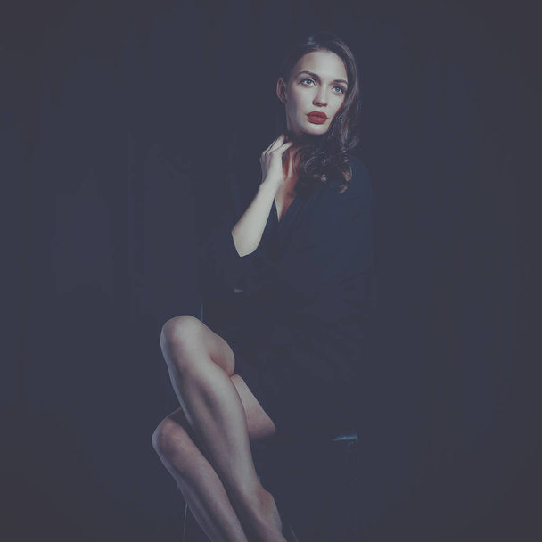 Beautiful woman sitting a chair, isolated on black background - Photo, Image