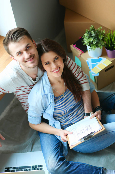 Молодая пара, сидящая на полу своей новой квартиры
 - Фото, изображение