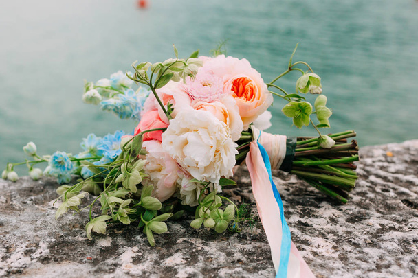 Wedding bouquet of peonies on the rocks by the sea. Wedding in M - Zdjęcie, obraz