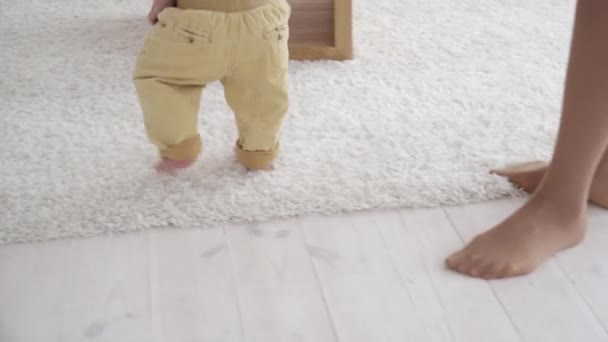 Mother helping her small son walk in the room, closeup - Séquence, vidéo