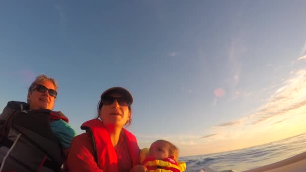 Een familie rijdt een boot op de Oceaan kust bij zonsondergang - Video