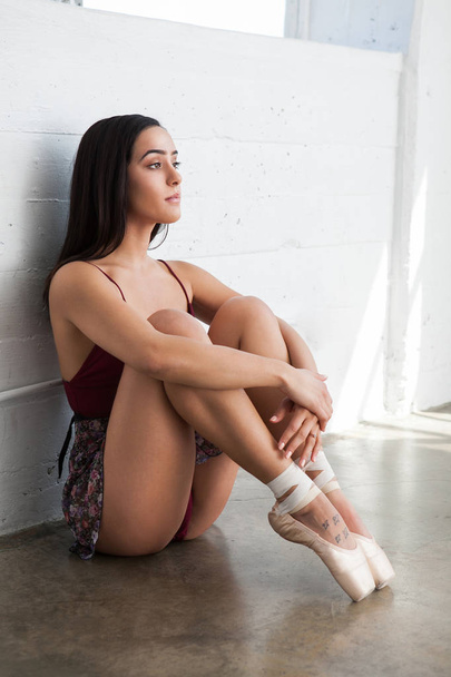 Sexy beautiful dancer woman in pointe shoes is sitting on the floor - Photo, image