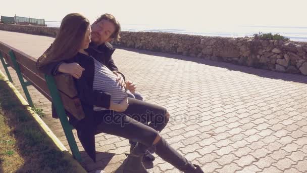 Пара влюбленных счастливых улыбающихся сидящих на скамейке перед мужчиной с беременным животом
 - Кадры, видео