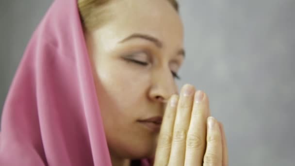 young woman in headscarf is praying. close-up female hands holding chain with a cross - Materiaali, video