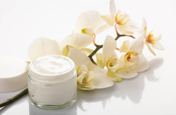 Hydraterende crème en orchid op witte achtergrond - Foto, afbeelding