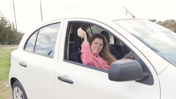 Felice giovane donna conducente in possesso di chiavi di auto alla guida della sua nuova auto
 - Filmati, video