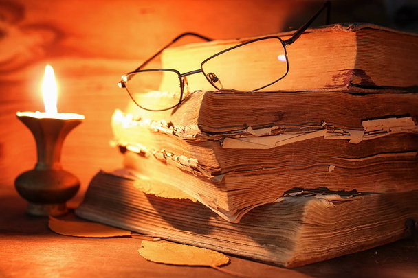 стара потайна книга на дерев'яному столі, освітлена свічками та окулярами
 - Фото, зображення