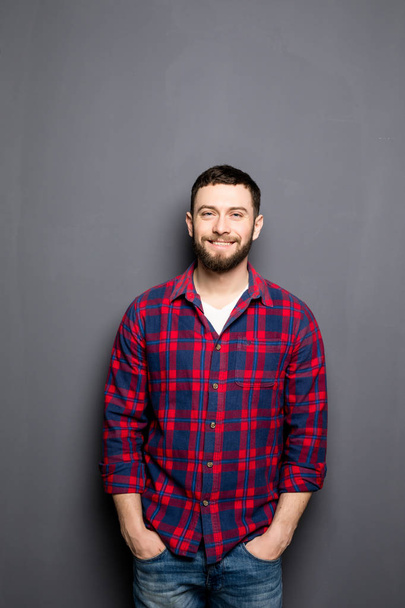 Счастливый молодой человек. Портрет красивого молодого человека в повседневной рубашке с руками в карманах и улыбкой
 - Фото, изображение