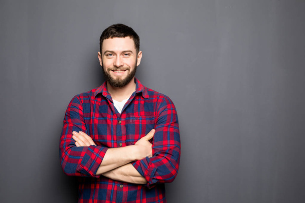Portrait of handsome young man in casual shirt keeping arms crossed and smiling - Foto, Imagem