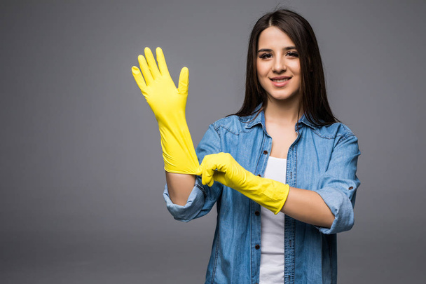 クリーニング女性がゴム手袋を履いて春の大掃除の準備ができて得る。灰色の背景に分離カメラで満足の笑みを浮かべて掃除婦. - 写真・画像