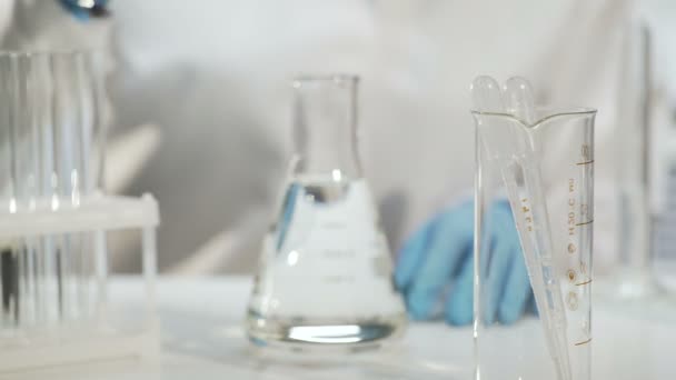 Químico añadiendo sustancia en frasco cónico con líquido, experimento químico
 - Imágenes, Vídeo