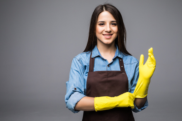 vrolijke huisvrouw handschoenen te zetten voordat u gaat schoonmaken - Foto, afbeelding