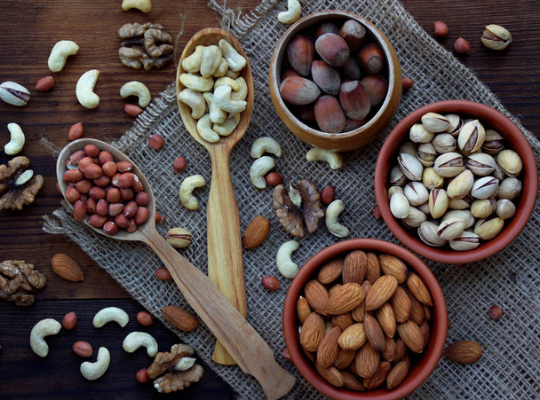 Une composition de différentes variétés de noix sur un fond en bois - amandes, noix de cajou, arachides, noix, noisettes, pistaches
. - Photo, image