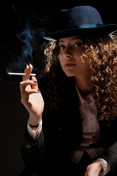 Beautiful woman standing and smoking on the black - Zdjęcie, obraz