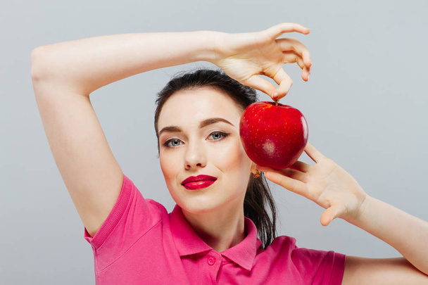A pretty woman taking a bite out of a red apple. - Foto, afbeelding
