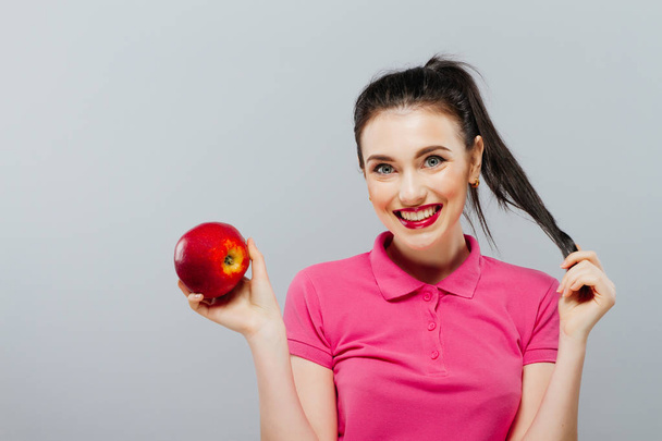 Portrait of a cute brunette with an apple , white background - Valokuva, kuva