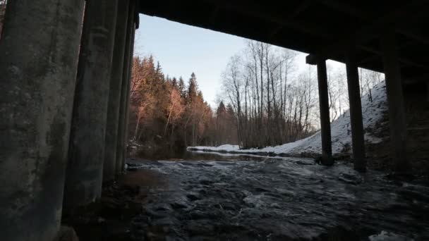 Movement of the river under the bridge in the early spring during the daytime. - Filmmaterial, Video